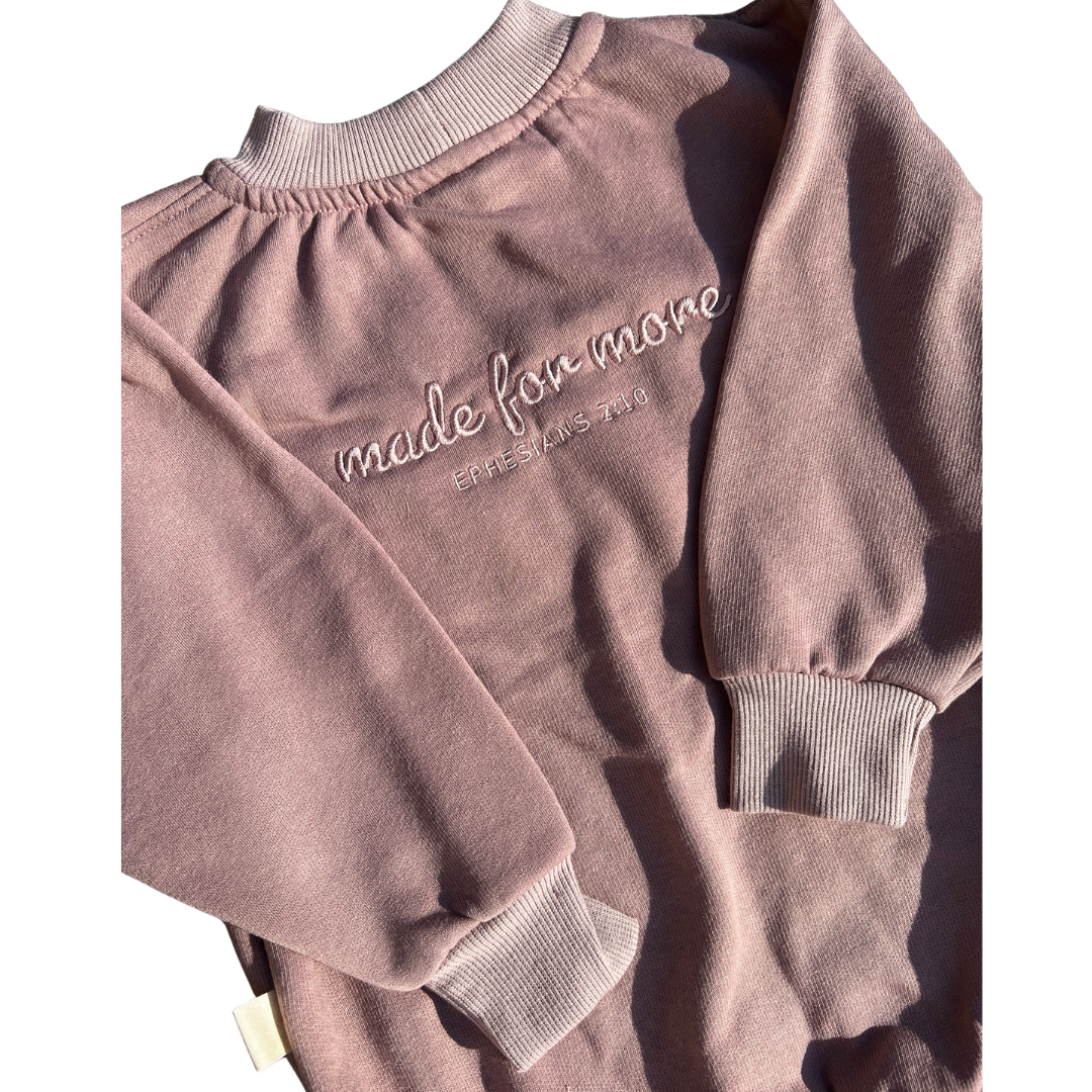 Pink sweatshirt with 'made for more' text on a white background