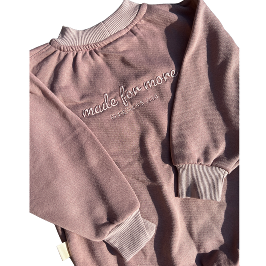 Pink sweatshirt with 'made for more' text on a white background
