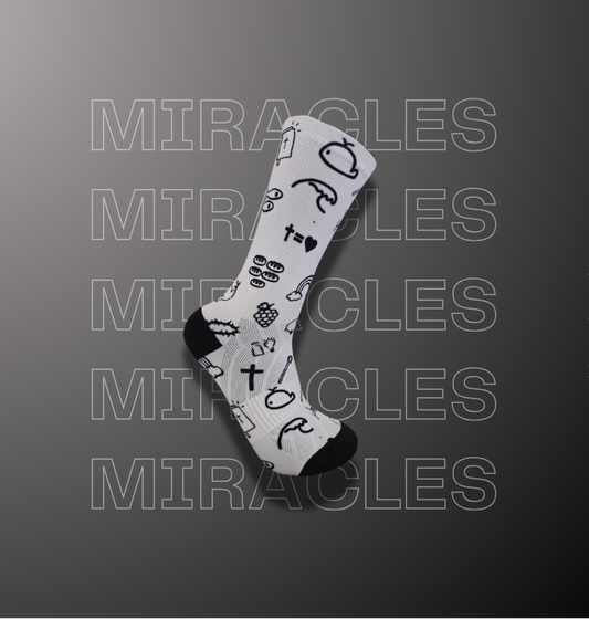 A single white crew sock with black graphic symbols and text, displayed diagonally on a dark gray background with repeated 'MIRACLES' watermark text.